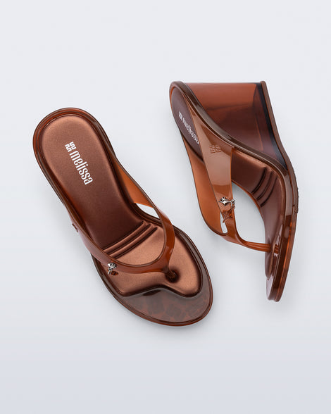 Top and side view of a pair of brown Nabeela wedge flip flops with star charm on strap