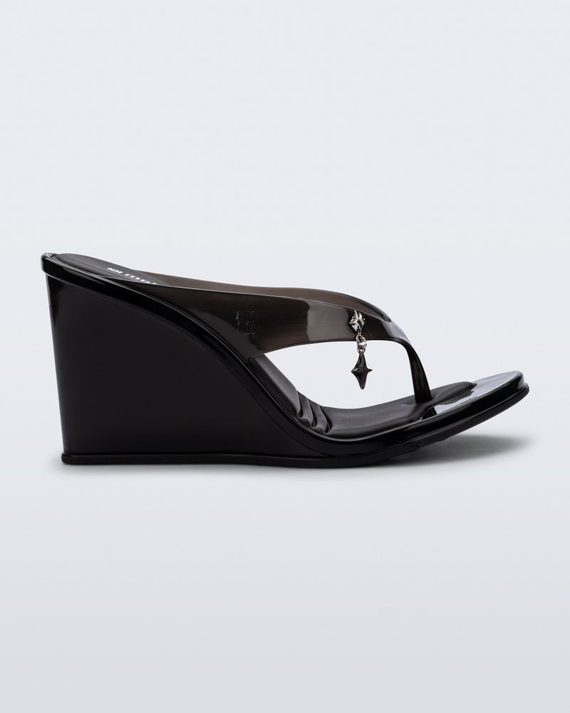 Side view of a black Nabeela wedge flip flop with star charm on strap