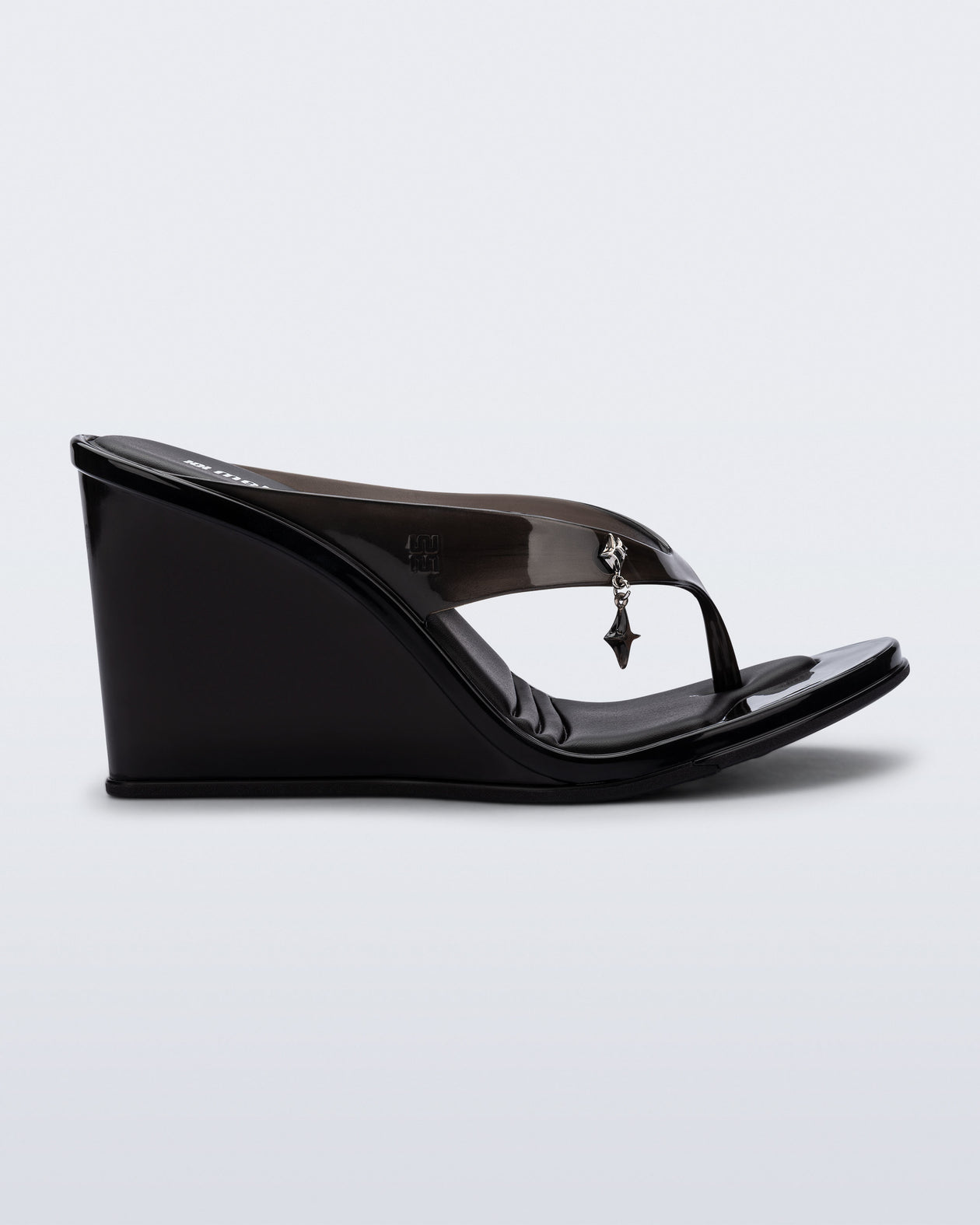 Side view of a black Nabeela wedge flip flop with star charm on strap