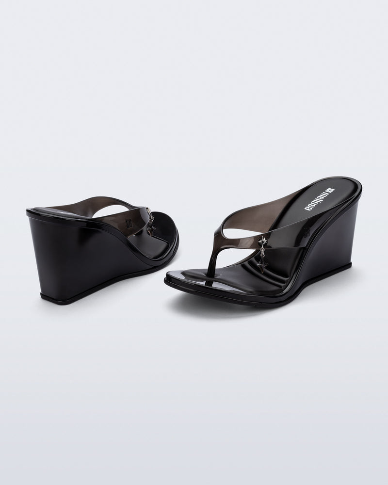 Back and angled view of a pair of black Nabeela wedge flip flops with star charm on strap
