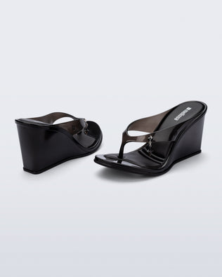Back and angled view of a pair of black Nabeela wedge flip flops with star charm on strap