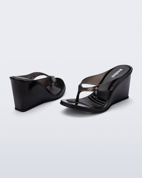Back and angled view of a pair of black Nabeela wedge flip flops with star charm on strap
