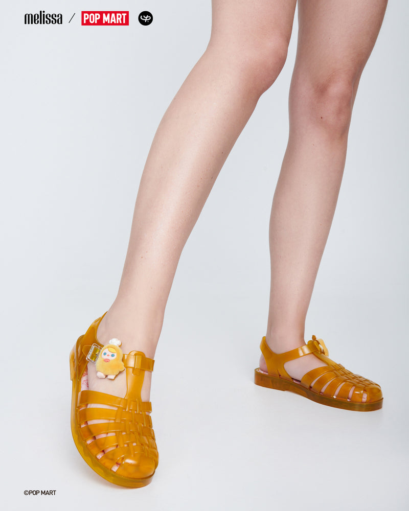 Model's legs wearing a pair of transparent yellow Possession + Pop Mart Pucky fisherman sandals