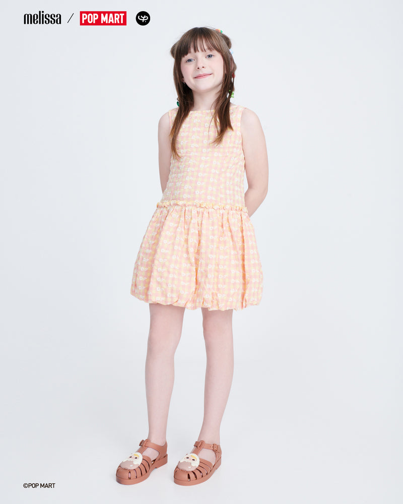 Child model in an orange and white dress wearing a pair of beige Possession + Pop Mart Pucky kids fisherman sandals