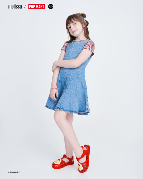 Child model in a denim dress wearing a pair of red Possession + Pop Mart Pucky kids fisherman sandals
