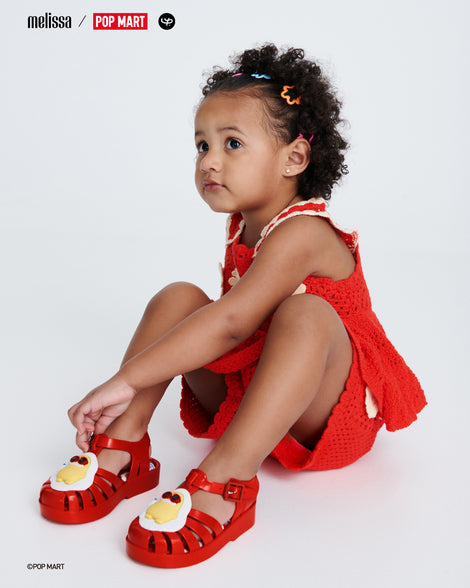 Child model in a red sleeveless dress wearing a pair of red Possession + Pop Mart Pucky baby fisherman sandals