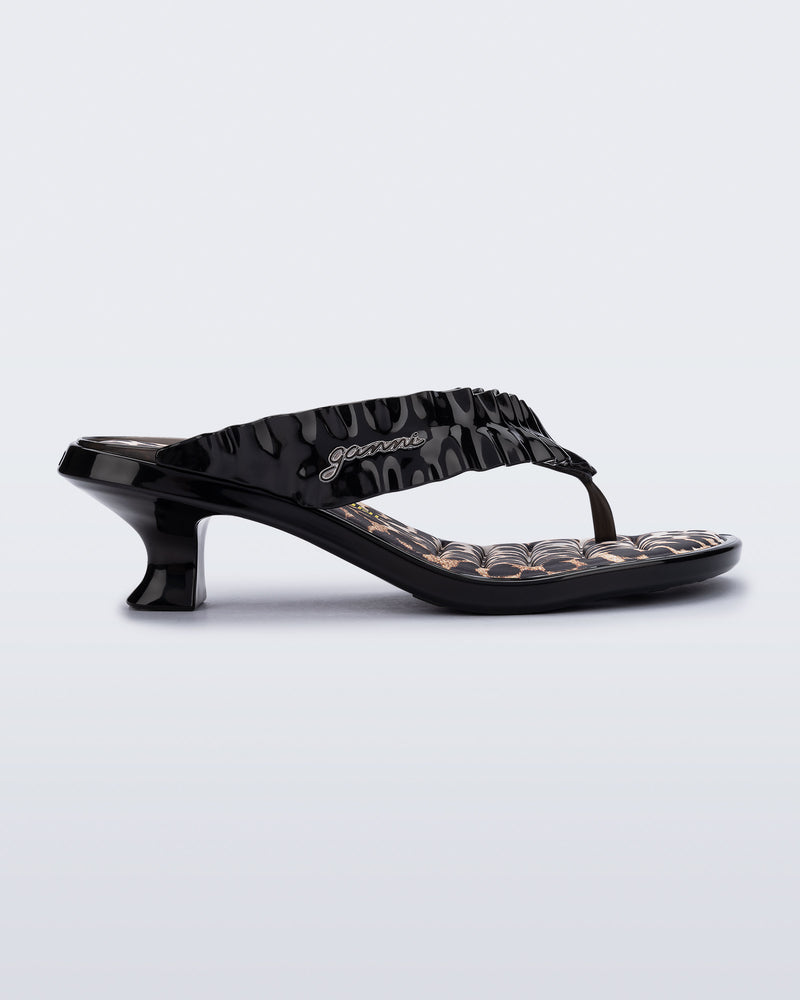 side view of a black Flip Flop Kitten Heel + GANNI sandal with leopard print foot bed and faux ruffle strap