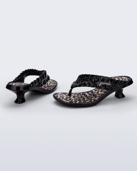 Back and side view of a pair of black Flip Flop Kitten Heel + GANNI sandals with leopard print foot bed and faux ruffle strap