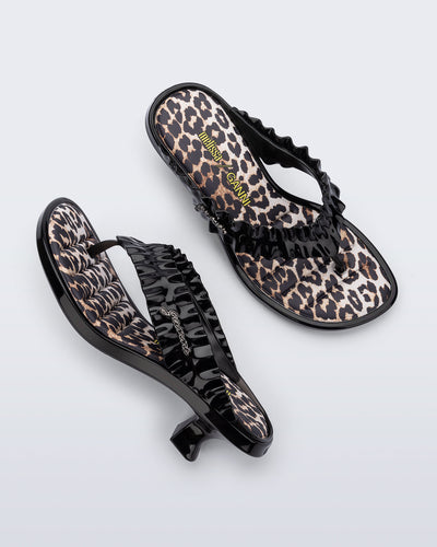 Top and side view of a pair of black Flip Flop Kitten Heel + GANNI sandals with leopard print foot bed and faux ruffle strap