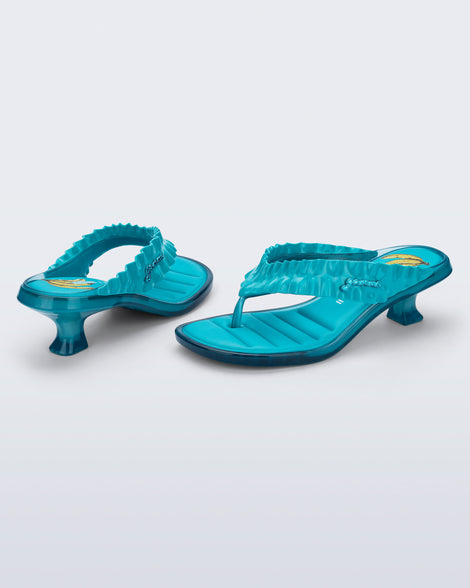 Back and side view of a pair of blue Flip Flop Kitten Heel + GANNI sandals with Banana print foot bed and faux ruffle strap