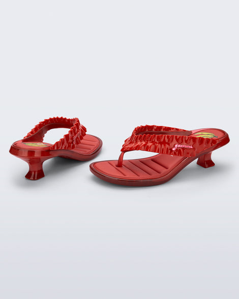 Back and side view of a pair of red Flip Flop Kitten Heel + GANNI sandals with cherry print foot bed and faux ruffle strap