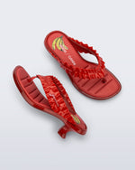 Top and side view of a pair of red Flip Flop Kitten Heel + GANNI sandals with banana print foot bed and faux ruffle strap