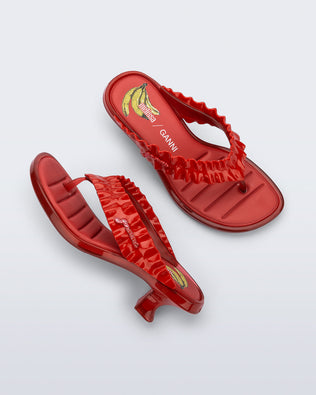 Top and side view of a pair of red Flip Flop Kitten Heel + GANNI sandals with banana print foot bed and faux ruffle strap