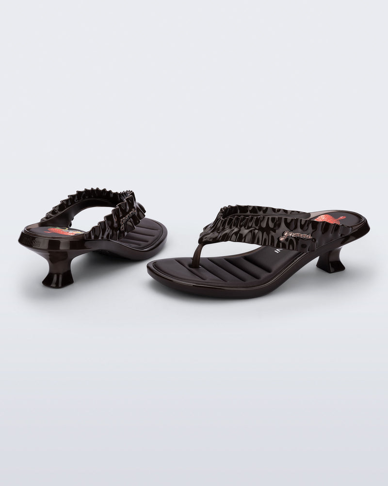Back and side view of a pair of brown Flip Flop Kitten Heel + GANNI sandals with strawberry print foot bed and faux ruffle strap