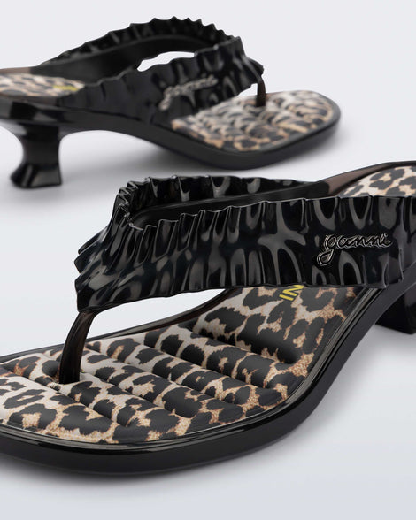 Close up angled view of a black Flip Flop Kitten Heel + GANNI sandals with leopard print foot bed and faux ruffle strap