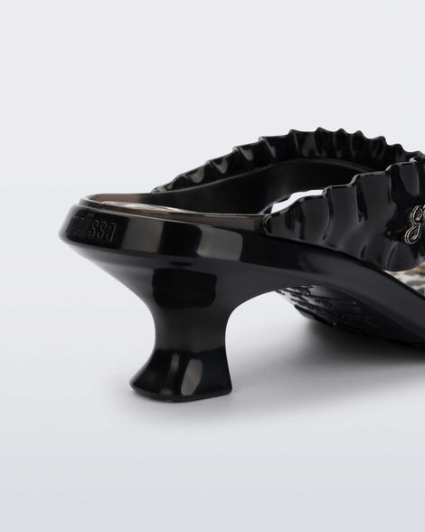 Close up view of the heel of a black Flip Flop Kitten Heel + GANNI sandal with leopard print foot bed and faux ruffle strap