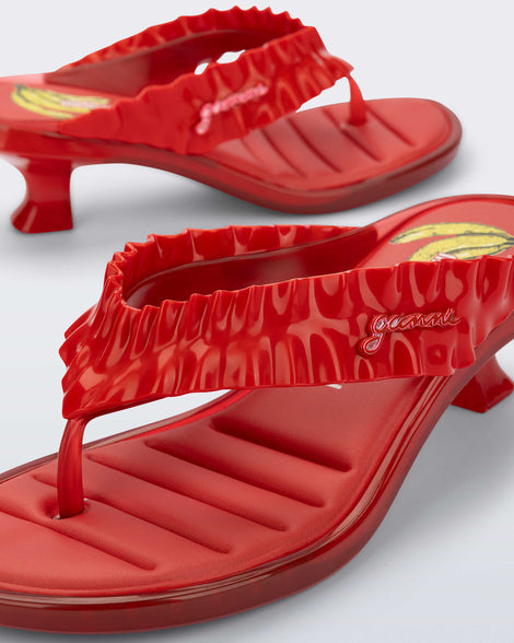 Close up angled view of a red Flip Flop Kitten Heel + GANNI sandal with banana print foot bed and faux ruffle strap