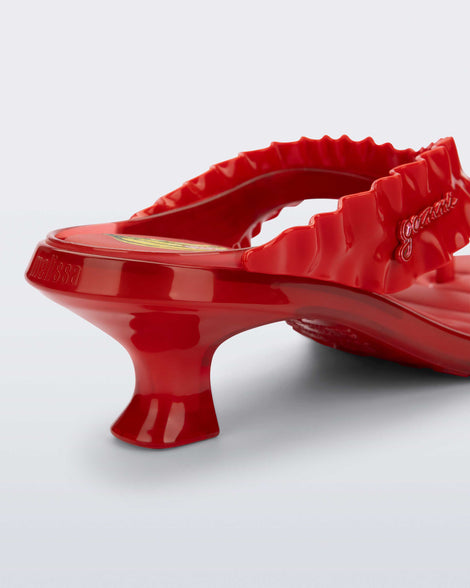 Close up view of the back heel of a  red Flip Flop Kitten Heel + GANNI sandal with banana print foot bed and faux ruffle strap