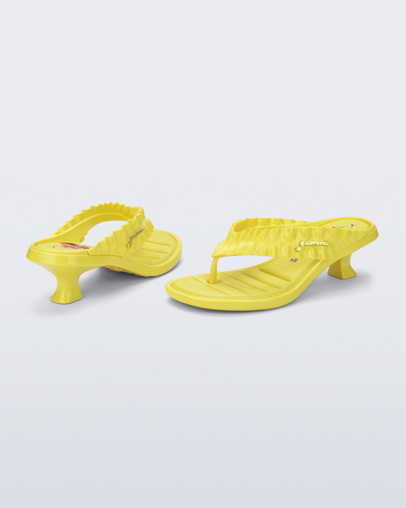 Back and side view of a pair of yellow Flip Flop Kitten Heel + GANNI sandals with cherry print foot bed and faux ruffle strap