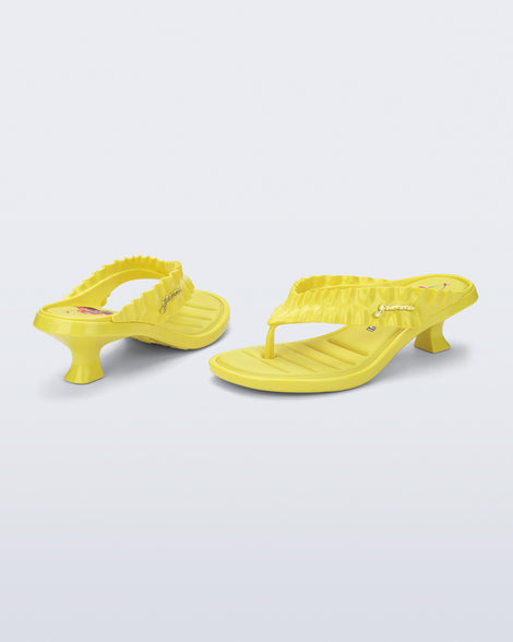 Back and side view of a pair of yellow Flip Flop Kitten Heel + GANNI sandals with cherry print foot bed and faux ruffle strap