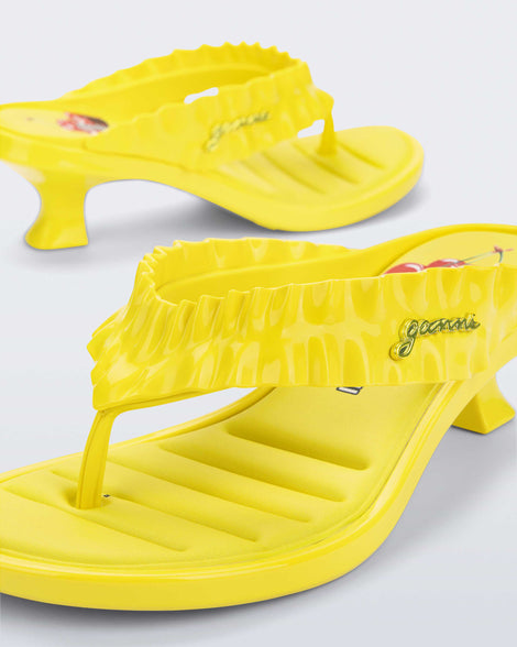 Close up angled view of a  yellow Flip Flop Kitten Heel + GANNI sandal with cherry print foot bed and faux ruffle strap