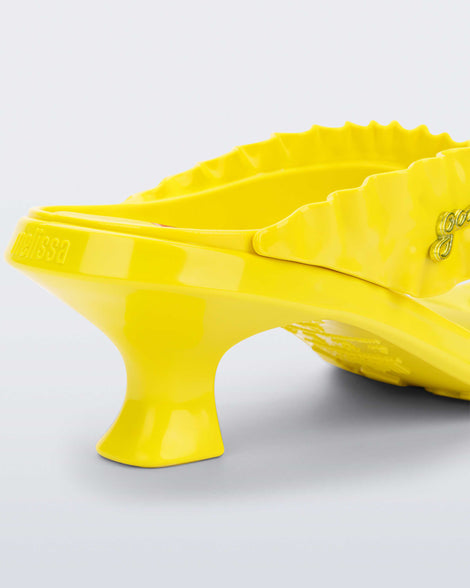 Close up view of the back heel of a  yellow Flip Flop Kitten Heel + GANNI sandal with cherry print foot bed and faux ruffle strap