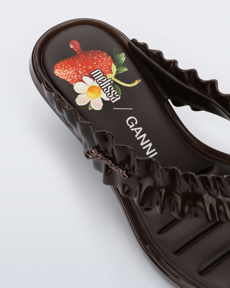Close up view of the heel of a brwon Flip Flop Kitten Heel + GANNI sandal with Banana print foot bed and faux ruffle strap