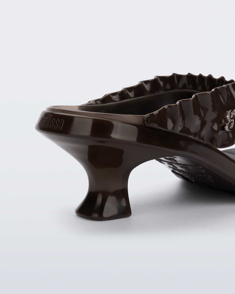 Close up view of the back heel of a brown Flip Flop Kitten Heel + GANNI sandal with Banana print foot bed and faux ruffle strap