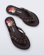 Top view of a pair of  brown Flip Flop Slim + GANNI sandals with a strawberry print foot bed and faux ruffle strap