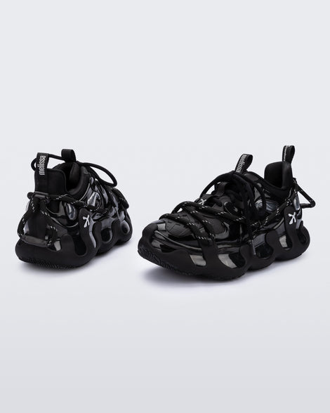 Side and back view of a pair of black with grey accents Melissa X Icon sneaker