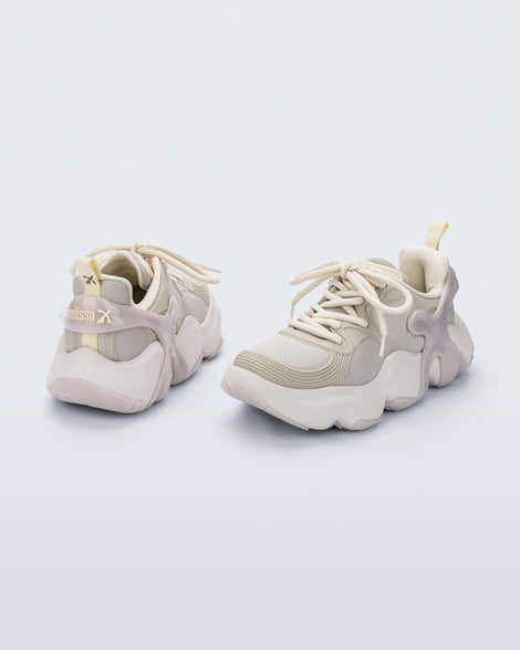 Side and back view of a pair of beige Melissa X Rush sneakers