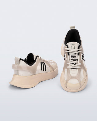 Top and back angle view of a pair of beige Melissa X Beat sneakers with black logo on a light gray background