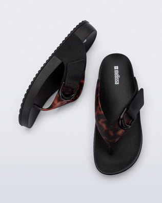 Top and side view of a pair of black Cozy Thong Flip flops with brown tortoise strap