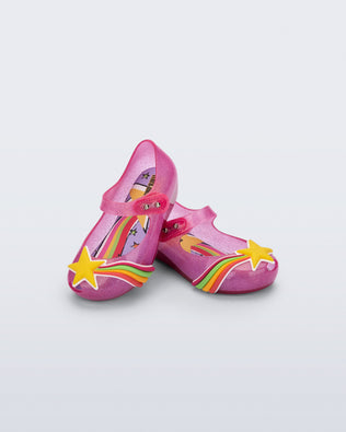 Angled view of a pair of glitter pink Ultragirl Colors baby flats with yellow star and rainbow on top