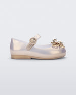 Side view of a pearly gold Mini Melissa Sweet Love Butterfly flat with a top strap and a gold butterfly detail on the toe