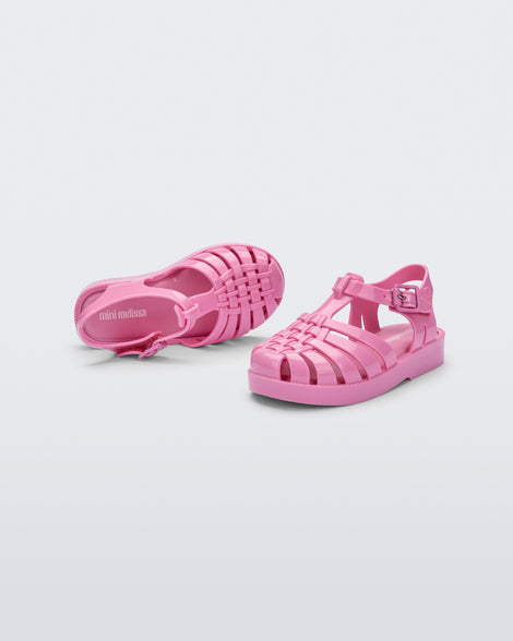An angled top and front view of a pair of pink Mini Melissa Possession sandals with a fisherman sandal design