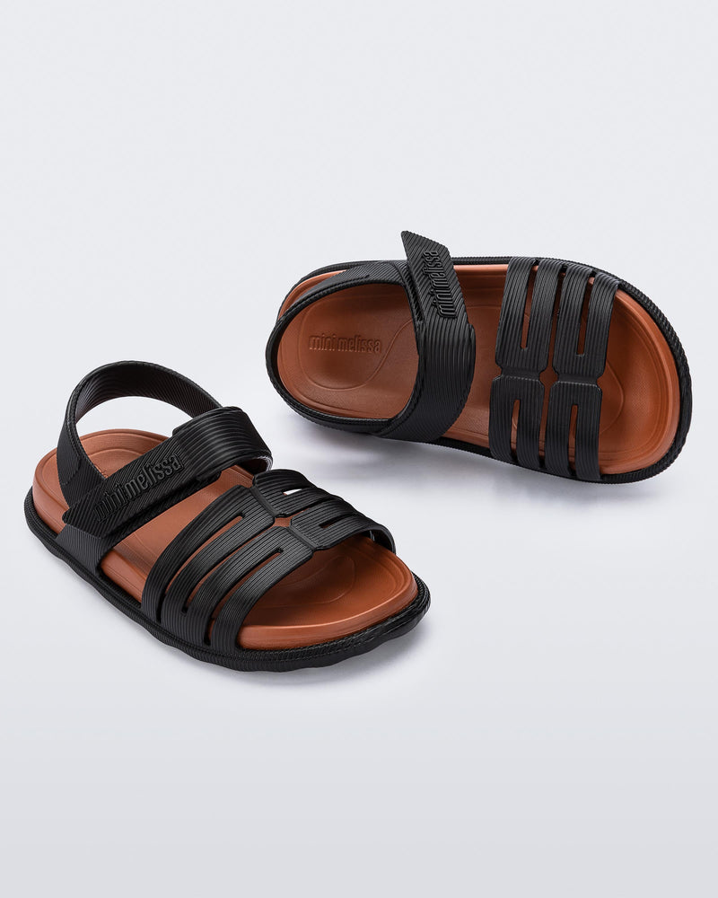 Top and angled view of a pair of black with brown insole Kaiteki baby sandals