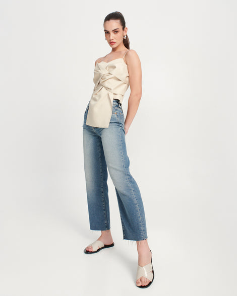 Model in jeans and a beige shirt wearing a pair of black Essential Cross Slide sandals with beige colored straps