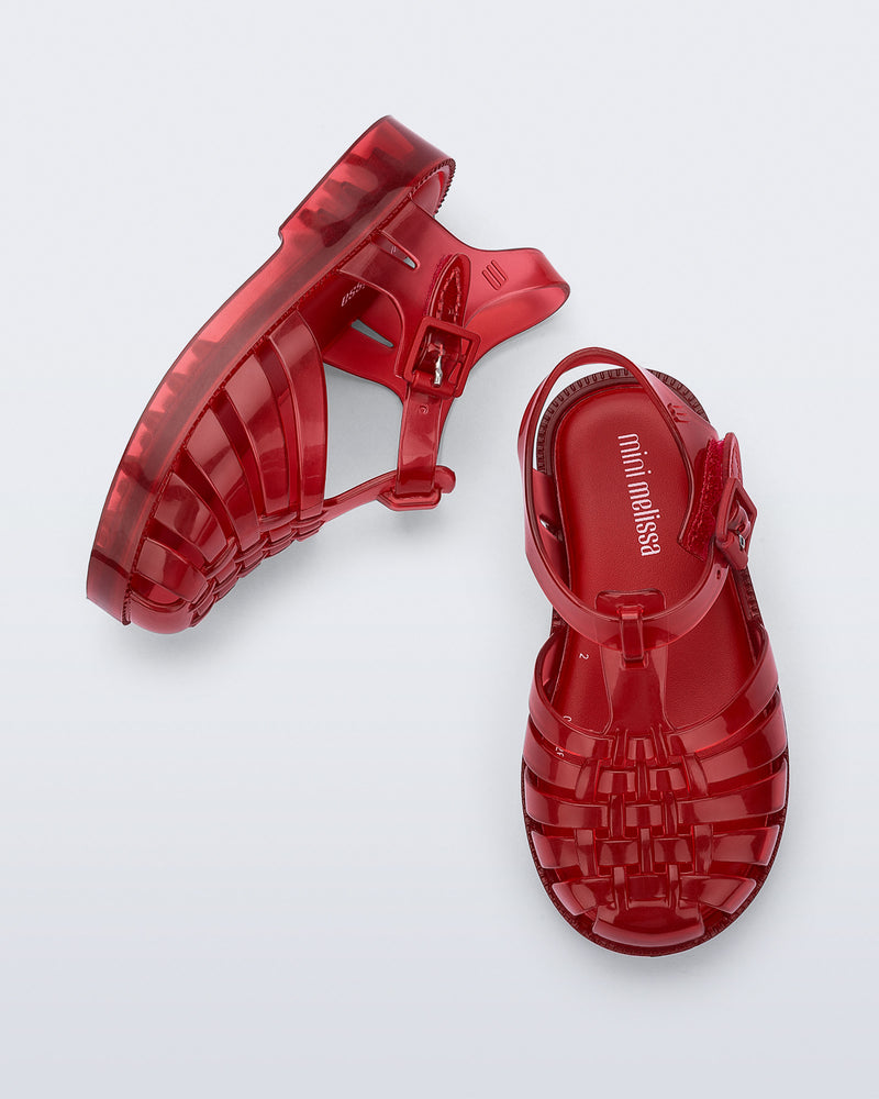 Side and top view of a pair of clear red Possession baby sandals