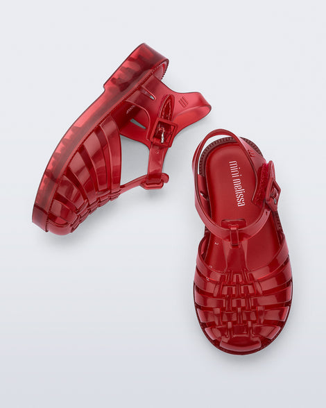 Side and top view of a pair of clear red Possession baby sandals