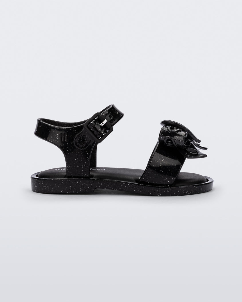 Side view of a glitter black Mini Melissa Mar Sandal Heart sandal with a glitter black heart bow detail on the front strap and an ankle strap