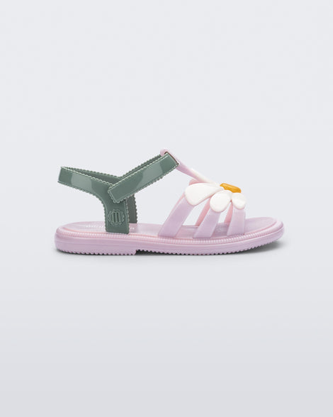 Side view of a  pink Hip Bloom baby sandal with white flower and green ankle strap