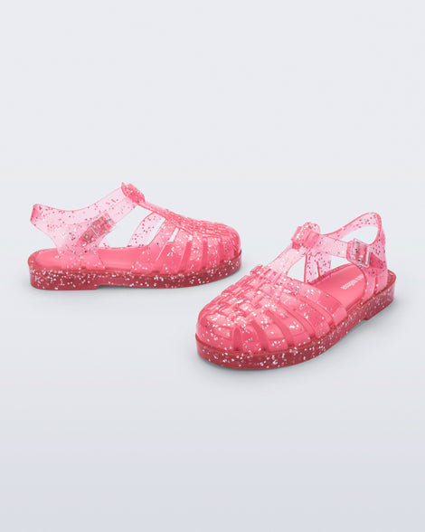 Side and angled view of a pair of pink Possession kids sandals with heart glitter