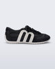 Side view of a black Motion sneaker with white colored sole and M monogram