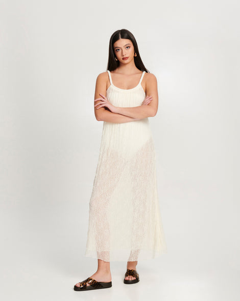 Model in a white dress wearing a pair of dark brown/tortoise Cozy Cross sandals with crisscross top straps