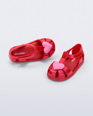 Side and top view of a pair of red Hip Heart Ballerina baby sandals with pink heart on front