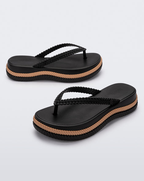 An angled front and side view of a pair of black/beige Melissa Leblon platform flip flops with details that mimic sisal braids on the sole and strap