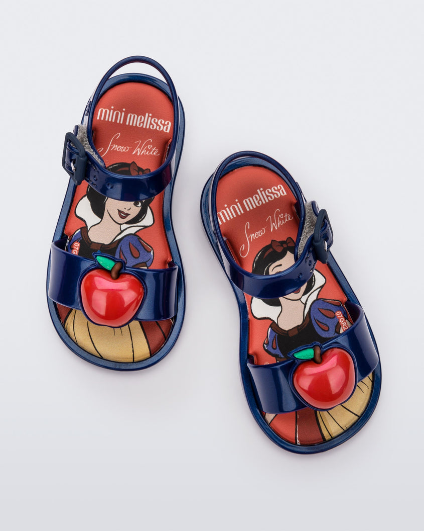 Top view of a pair of metallic blue Mini Melissa Mar Sandal Princess sandals with an apple detail on the front strap, an ankle strap and Princess Snow White soul