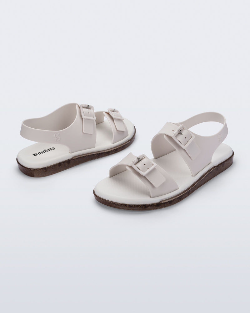 Side and angled view of a pair of beige Wave Sandals with two straps with buckles and a back strap