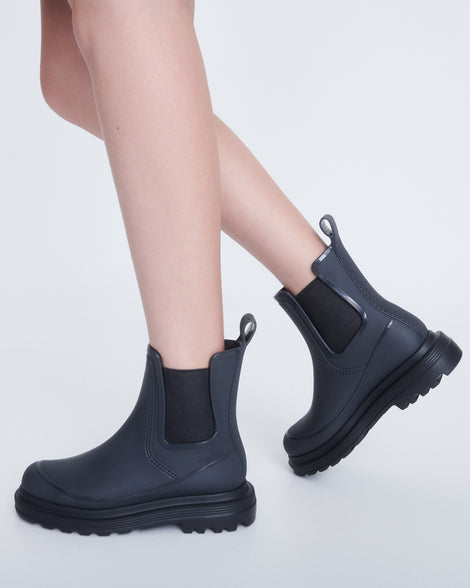 Model's legs wearing a pair of grey Noir boots with black sole